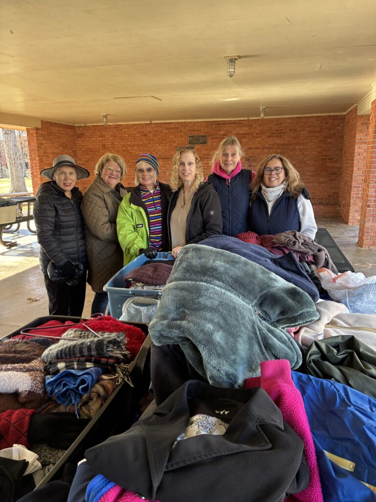 A group of six women stands together at a community event