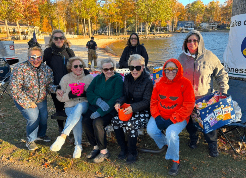 A group of eight women, dressed in fall attire and Halloween-themed outfits